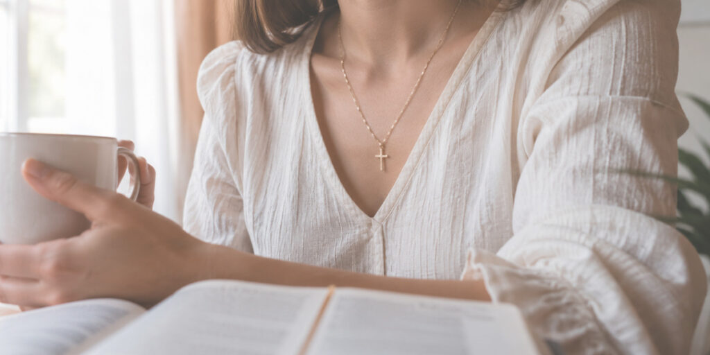 Mulher usando colar com cruz durante momento de leitura